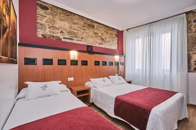 two beds in a hotel room with red walls at Hotel Entrecercas in Santiago de Compostela