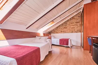 two beds in a room with a brick wall at Hotel Entrecercas in Santiago de Compostela