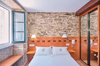 a bed in a room with a stone wall at Hotel Entrecercas in Santiago de Compostela