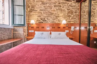 a bedroom with a large bed with a red blanket at Hotel Entrecercas in Santiago de Compostela
