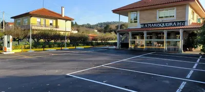 a parking lot with a tennis court in front of a building at Hotel A Marisqueira I Aeropuerto A Coruña in Oleiros