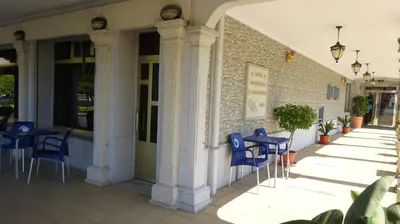 a patio with blue chairs and tables on a building at Hotel A Marisqueira I Aeropuerto A Coruña in Oleiros