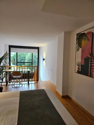 a room with a bed and a table and a balcony at Apartamentos Ciudad Santiago in Santiago de Compostela