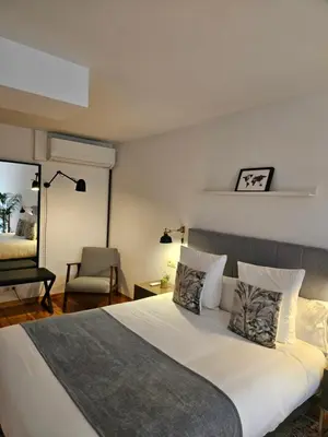 a bedroom with a large white bed with a chair at Apartamentos Ciudad Santiago in Santiago de Compostela