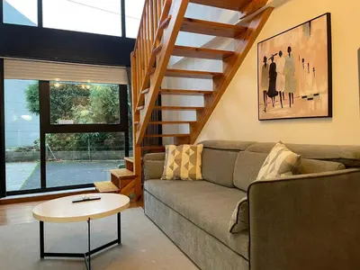 a living room with a couch and a staircase at Apartamentos Ciudad Santiago in Santiago de Compostela