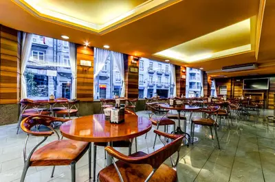 a restaurant with wooden tables and chairs and windows at Hotel Princess in Ourense