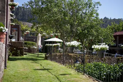 a garden with a fence with flowers and an umbrella at Casa Grande Do Bachao in Santiago de Compostela