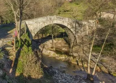 a stone bridge over a river in a field at Casa da Pilar - A Ponte in Portomourisco