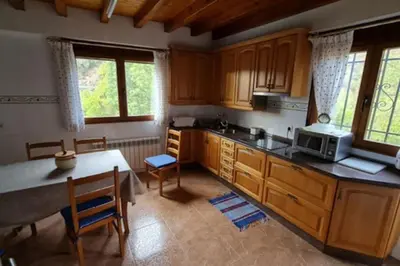 a kitchen with wooden cabinets and a table with a microwave at Casa da Pilar - A Ponte in Portomourisco