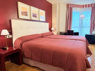 a red bedroom with a large bed and a window at Hotel Bouza in Ribadeo