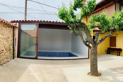 a courtyard with a tree in front of a house at Astorga. León. Piscina. Casa Val de San Lorenzo. in Val de San Lorenzo