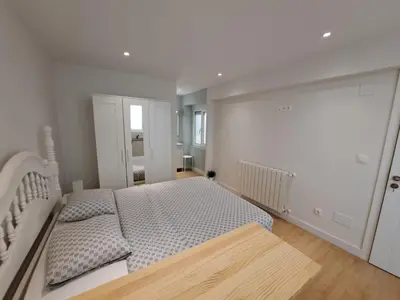 a white bedroom with a bed and a wooden floor at VISTAS MURALLA CENTRICO EN ZONA PEATONAL Wi-fi VUT LU 3270 in Lugo