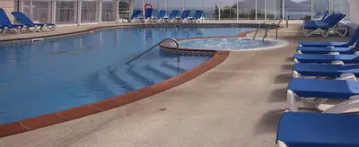 a large swimming pool with blue chairs in a building at Hotel Las Sirenas in Viveiro
