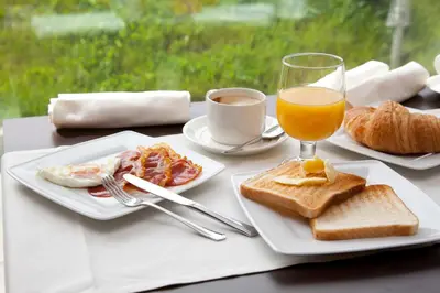 a table with two plates of food and a glass of orange juice at Hotel Las Sirenas in Viveiro