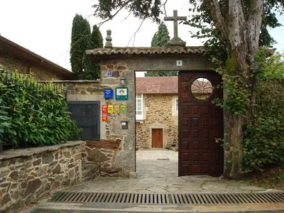 a church with a wooden door and a cross at Pazo Xan Xordo in Lavacolla