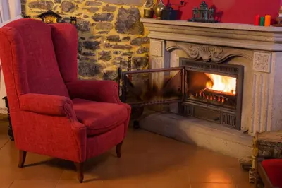 a red chair sitting in front of a fireplace at Pazo Xan Xordo in Lavacolla