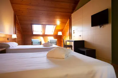 a hotel room with two beds and a flat screen tv at IBERIK Augas Santas Balneario & Golf in Pantón
