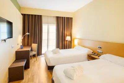 a hotel room with two beds and a television at IBERIK Augas Santas Balneario & Golf in Pantón