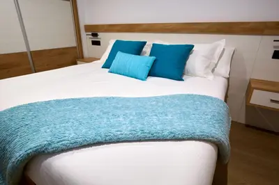 a bed with two blue pillows on top of it at HAVANAAPARTAMENTOS in Puerto de Vega