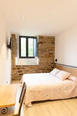 a bedroom with a bed and a brick wall at Hotel Casa da Luz in Pastoriza
