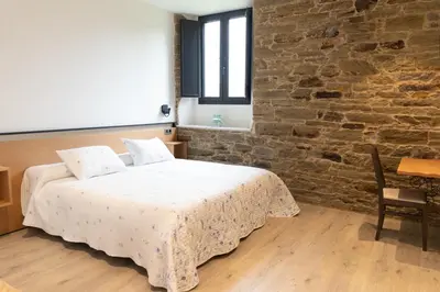 a bedroom with a bed and a brick wall at Hotel Casa da Luz in Pastoriza
