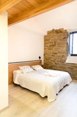 a bedroom with a bed and a stone wall at Hotel Casa da Luz in Pastoriza