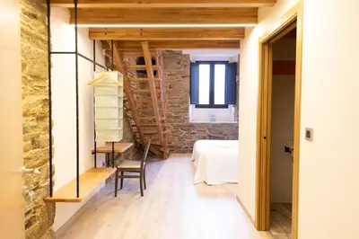 a room with a stone wall and a table and chair at Hotel Casa da Luz in Pastoriza