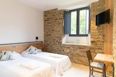 a room with two beds and a tv and a window at Hotel Casa da Luz in Pastoriza