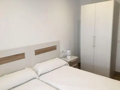 a white bedroom with two white beds and a cabinet at Carmarez in Puerto de Vega