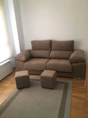 a living room with a brown couch and two stools at Carmarez in Puerto de Vega