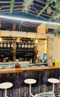 a bar with two stools and a counter with wine glasses at Hotel Cadario 1925 in Tebongo