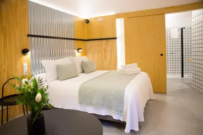 a bedroom with a bed with white sheets and a table at KALIDAS HOSTEL SUITES in Caldas de Reis