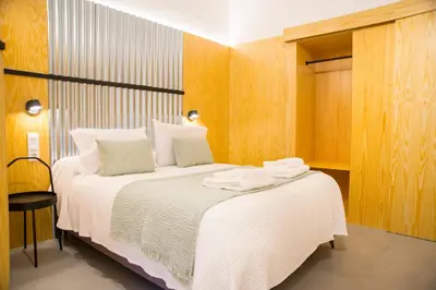 a bedroom with a large white bed with wooden walls at KALIDAS HOSTEL SUITES in Caldas de Reis