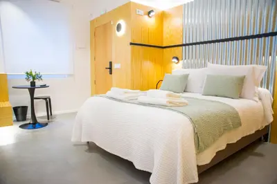 a bedroom with a large white bed with a wooden headboard at KALIDAS HOSTEL SUITES in Caldas de Reis
