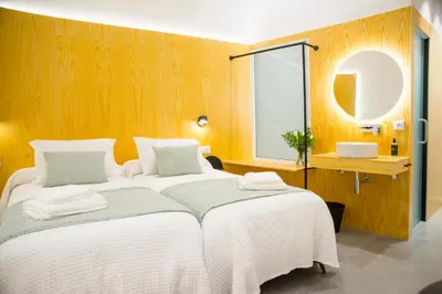 a bedroom with two beds and a sink and a mirror at KALIDAS HOSTEL SUITES in Caldas de Reis