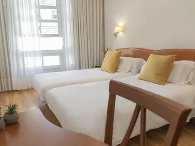 a hotel room with two beds and a window at Hostal ALBA Lugo in Lugo