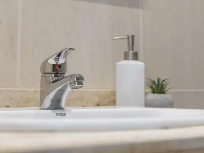 a bathroom sink with a faucet and a bottle of soap at Hostal ALBA Lugo in Lugo