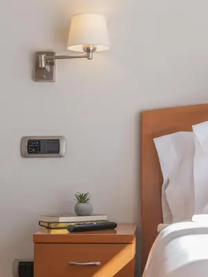 a bed with a nightstand with a clock and a plant on it at Hostal ALBA Lugo in Lugo
