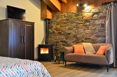 a bedroom with a couch and a stone wall at El Castro de Oscos in Murias