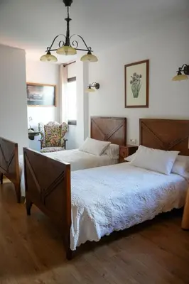 a bedroom with two beds and a chair at Hotel Rústico Fonteverde in Cuntis