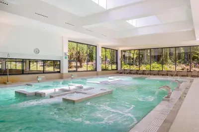 a large indoor pool with chairs and windows at Iberik Gran Balneario de Guitiriz in Guitiriz