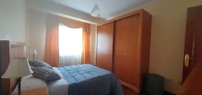 a bedroom with a bed with a blue blanket and a window at Apartamento A Pampillosa in Fazouro