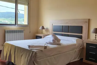 a bedroom with a large white bed with a window at Apartamento A Pampillosa in Fazouro