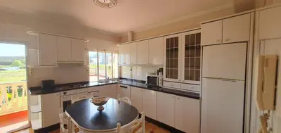 a kitchen with white cabinets and a table in it at Apartamento A Pampillosa in Fazouro