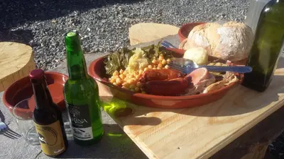 a plate of food and two bottles of wine at Sons do Eo- Apartamentos ecológicos en la montaña de Lugo in Baleira