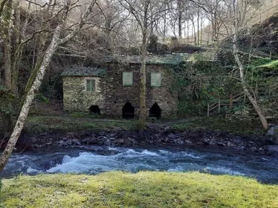 an old stone house next to a river at Sons do Eo- Apartamentos ecológicos en la montaña de Lugo in Baleira