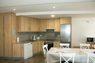 a kitchen with wooden cabinets and a table with chairs at Sensacional Apartamento Saladina Home in Ourense