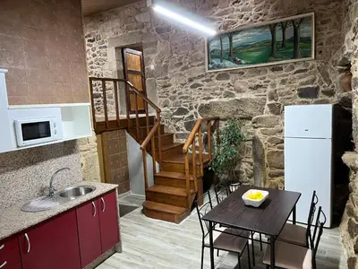 a kitchen and dining room with a table and a refrigerator at Casa Xulián in Monterroso
