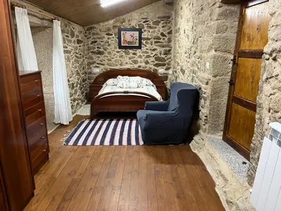 a bedroom with a bed in a stone wall at Casa Xulián in Monterroso
