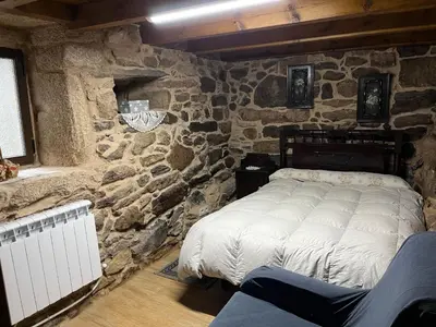 a bedroom with a stone wall with a bed at Casa Xulián in Monterroso